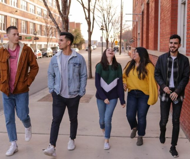 Teenagers walk along the street laughing